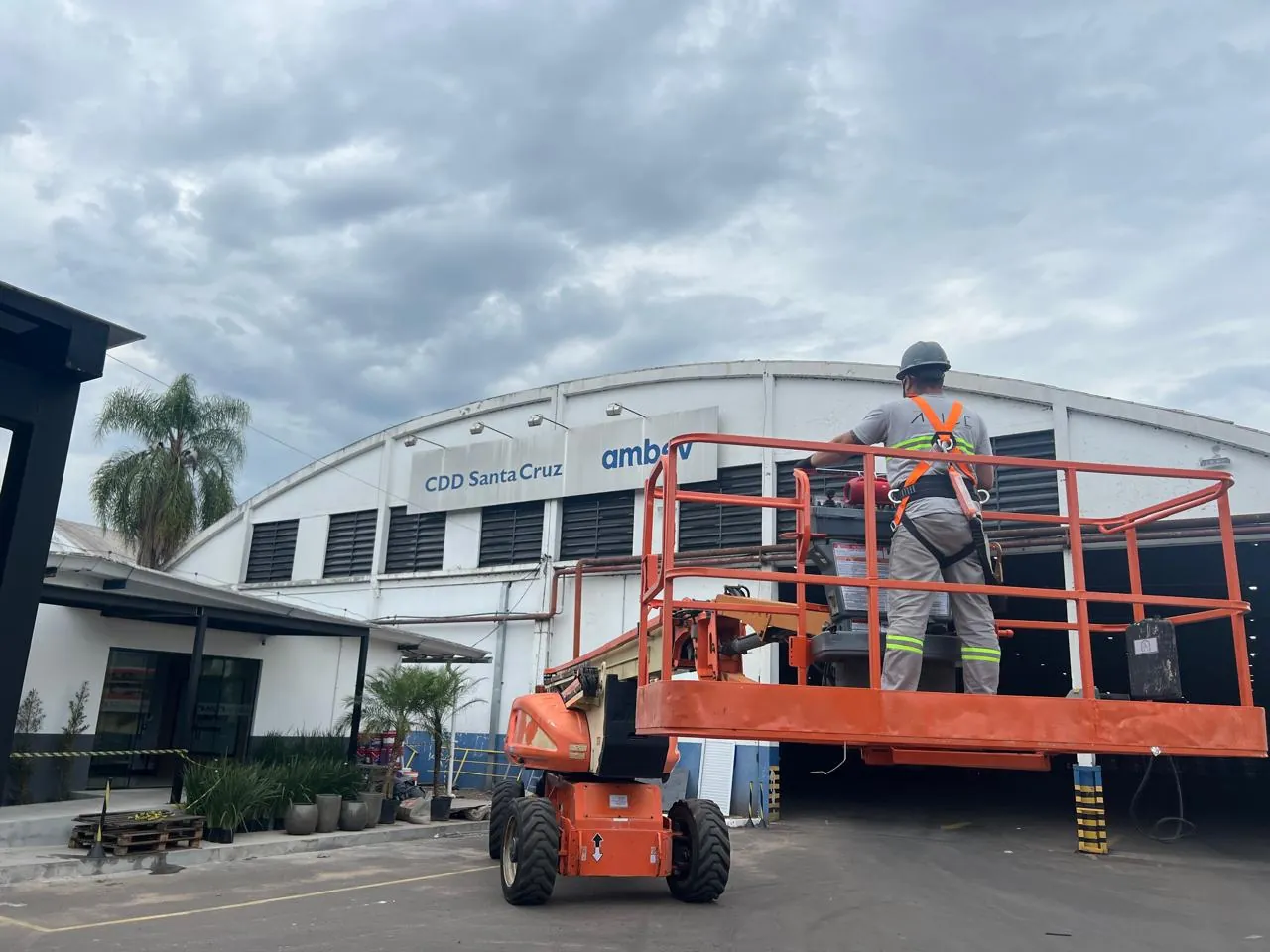 Profissional da Ápice em plataforma elevatória durante serviço na fachada do centro de distribuição.