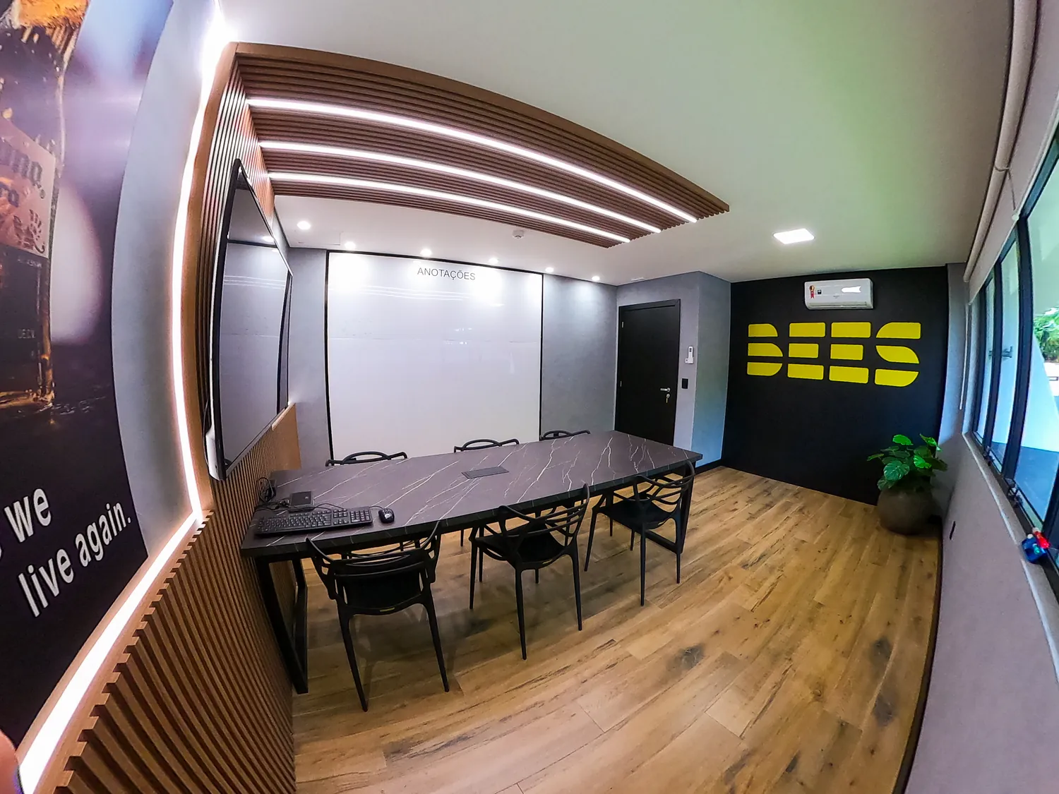 Sala de reunião com forro curvo iluminado e painel ripado de madeira.