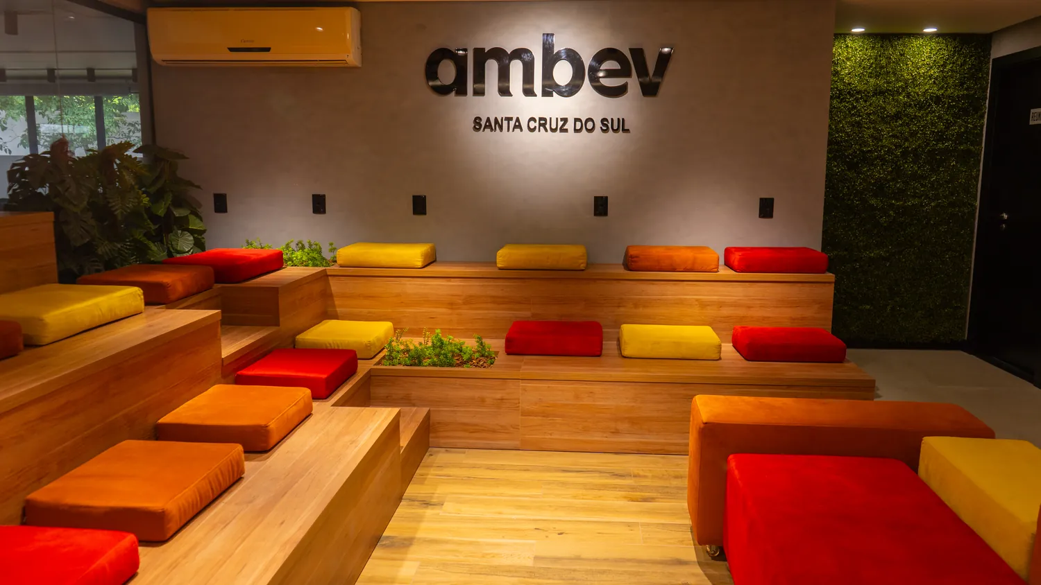 Auditório em arquibancada de madeira com almofadas coloridas, no centro de distribuição da Ambev em Santa Cruz do Sul.