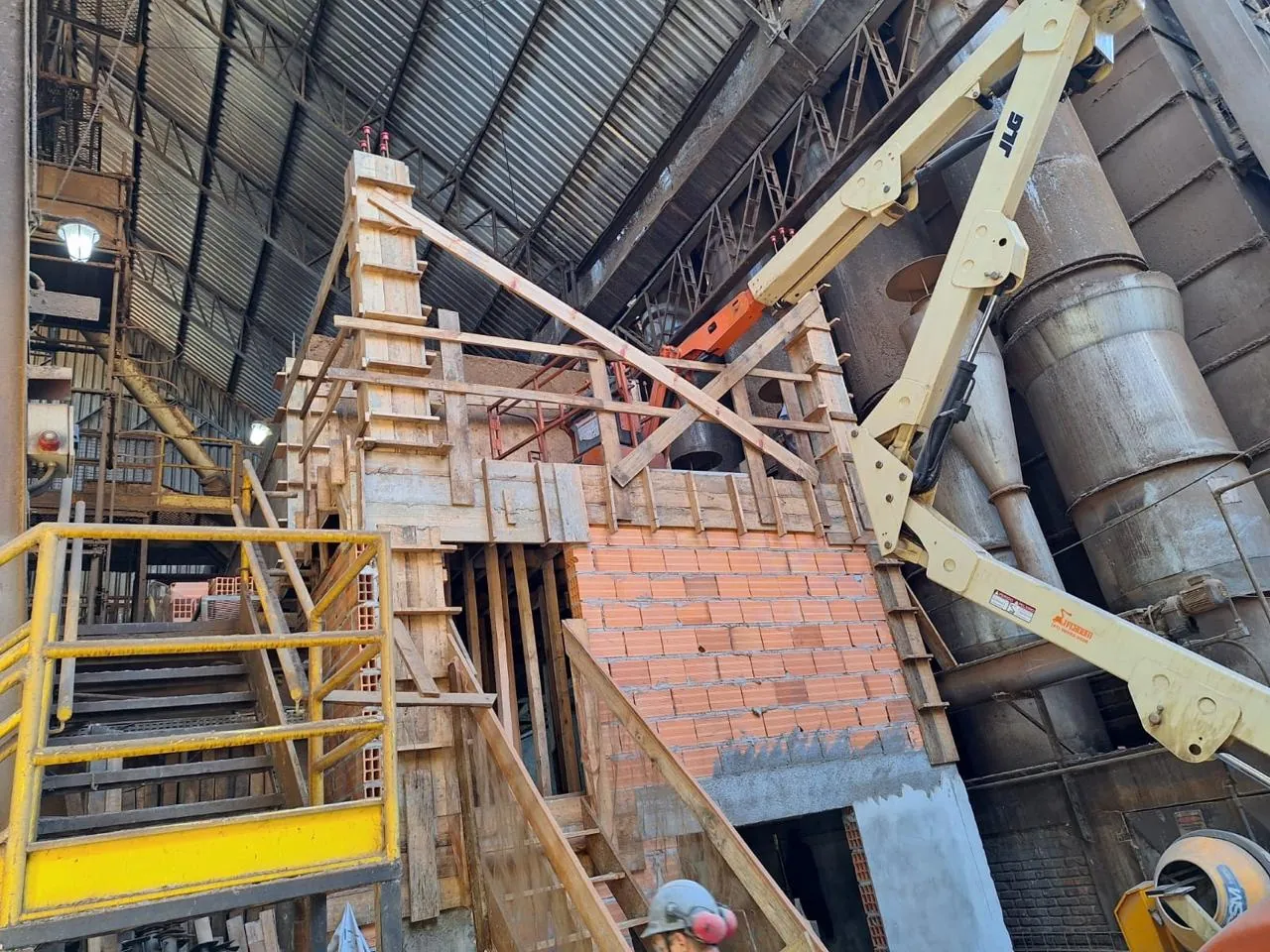 Escoramento e alvenaria estrutural executados entre silos e tubulações de uma planta industrial em operação.