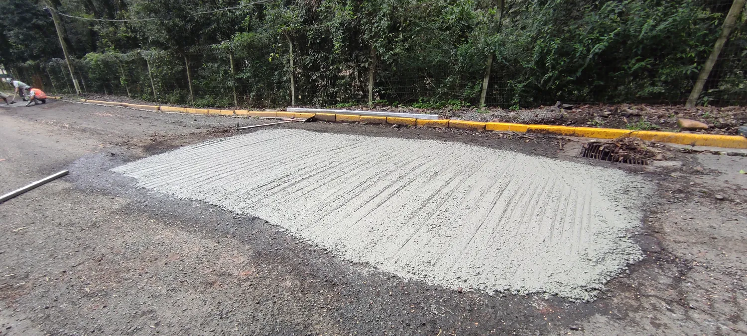 Trecho de pavimento rígido de concreto recém-concretado em via de acesso.